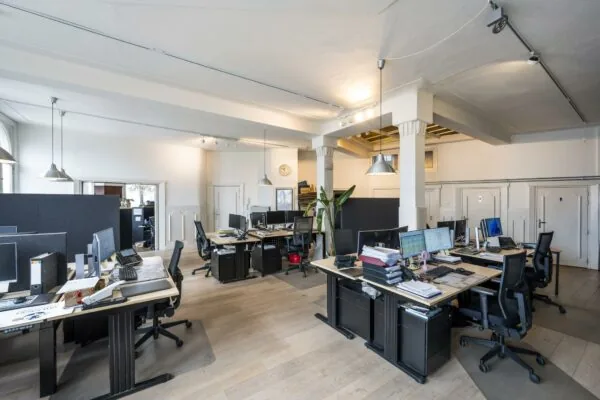 Ruim en licht kantoorinterieur aan de De Ruijterkade met meerdere werkplekken, computers en moderne inrichting.